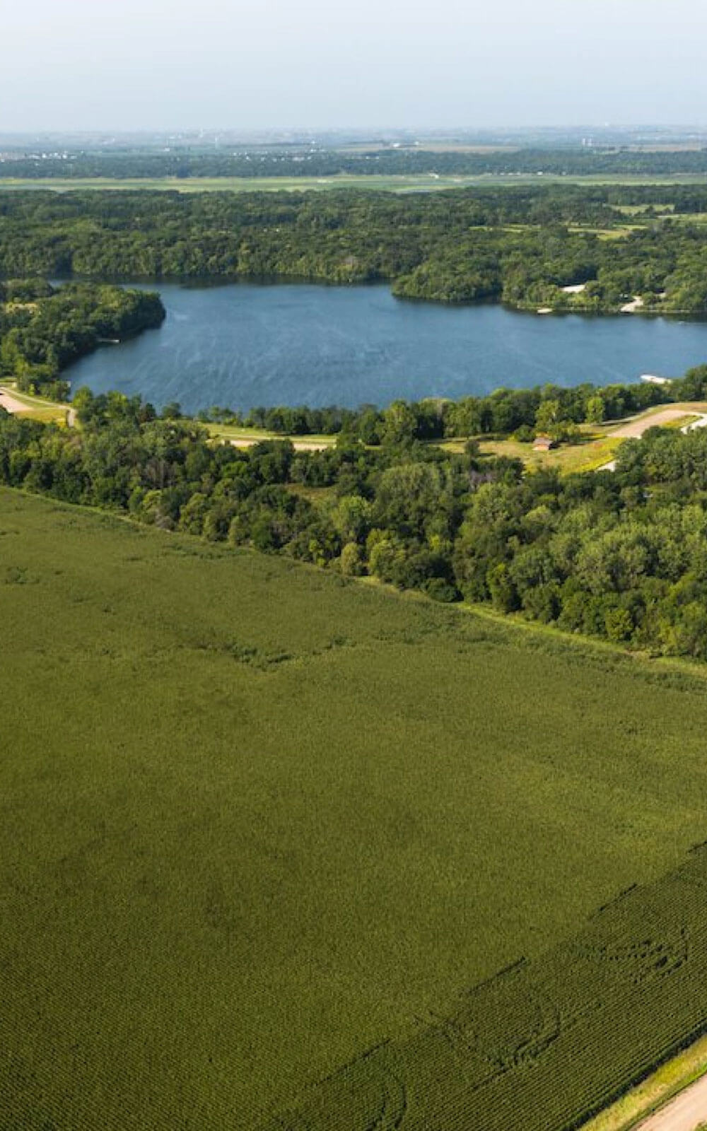 Aerial photography of a lush green field nearby a lake